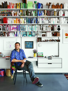 a man sitting on a chair in front of a bookshelf