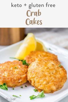 two crab cakes on a white plate with lemon wedges and keto - gluten free