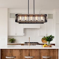 a kitchen island with stools and lights hanging from it's ceiling over the counter