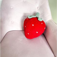 a crocheted strawberry sitting on top of a white chair next to a pillow