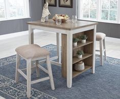 a kitchen table with two stools in front of it and an area rug on the floor