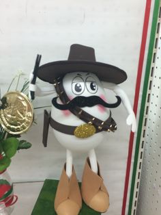 a figurine with a mustache and hat on it's head, standing next to a potted plant