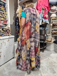 a woman in a hat is looking at some clothes on racks and she has her back turned to the camera