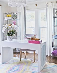 a white desk in the middle of a living room with lots of furniture and decor