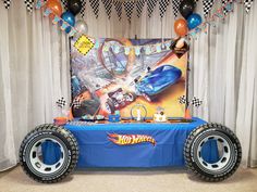 a blue table topped with two giant tires and balloon decorations in front of a backdrop