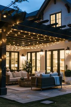 an outdoor living area with patio furniture and string lights on the pergolated roof