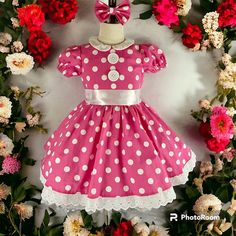 a pink and white dress with polka dots on it, surrounded by red and white flowers