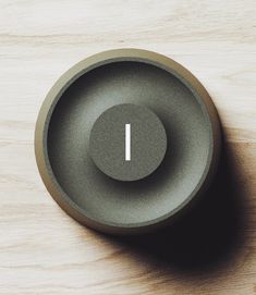 a gray bowl sitting on top of a wooden table next to a white object with an i in the middle