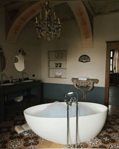 a large bathtub sitting in the middle of a bathroom next to a chandelier