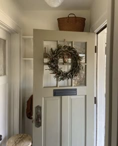 a white door with a wreath on it and a wooden bench in front of it