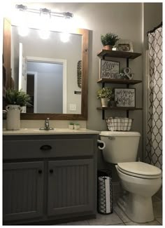 a white toilet sitting next to a sink in a bathroom under a mirror with shelves above it