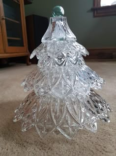 a clear glass christmas tree sitting on the floor