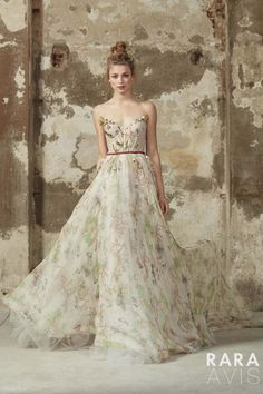 a woman standing in front of an old wall wearing a dress with flowers on it