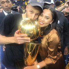 a man and woman posing with a basketball trophy