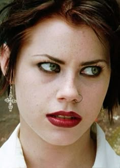 a close up of a woman with blue eyes and red lipstick on her face, looking at the camera