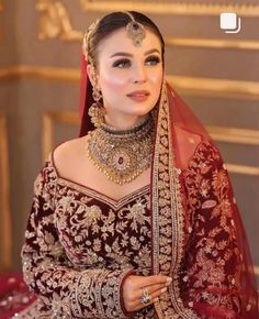 a woman wearing a red and gold bridal outfit