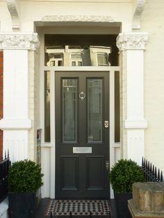 a black front door with two potted plants