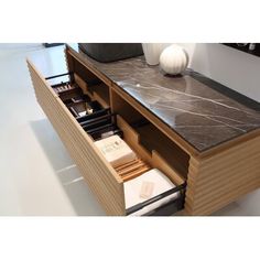 an open drawer in a wooden cabinet with marble counter top and drawers on both sides