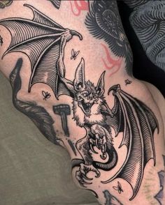 a man's arm with a tattoo on it that has a bat and demon on it