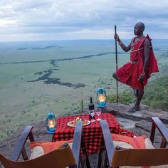 a man standing on top of a cliff next to a table