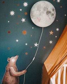 a child's room painted with stars and a bear holding a string to the moon