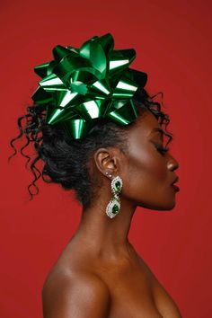 a woman with a green bow on her head and earrings in front of a red background