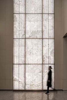 a person standing in front of a wall with large glass panels on the walls and floor