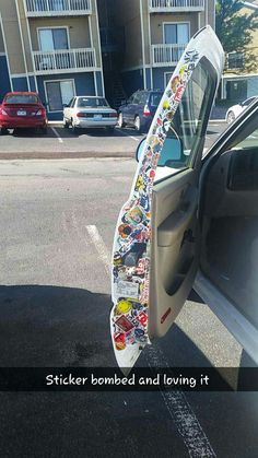 a surfboard sticking out of the side of a car door with sticker bombed and loving it