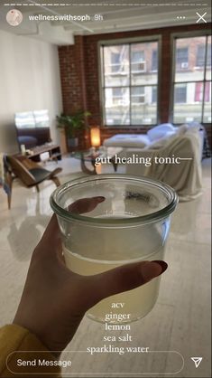 a person holding a glass bowl filled with water in front of a living room window