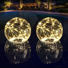 two lighted balls sitting on top of a pool