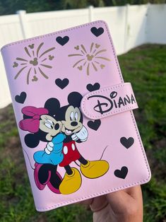 a person holding up a pink mickey mouse passport case