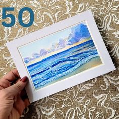 someone is holding up a watercolor painting with the words 50 on it and an image of