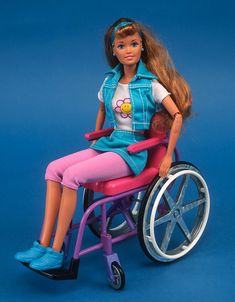 a barbie doll sitting in a wheel chair on a blue background stock - fotop