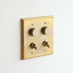 an electrical outlet on the wall with four knobs and two switches in gold color