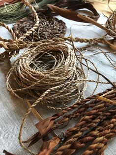 several bundles of twine on a table with other items in the back ground, including leaves and twigs