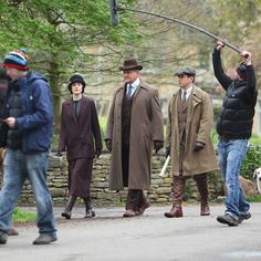 a group of people that are standing in the street with one man holding an umbrella