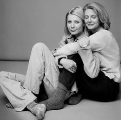 two women are sitting on the floor posing for a black and white photo with their arms around each other