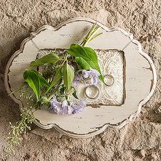 an old tray with flowers and candles on it is sitting on the ground next to some rocks