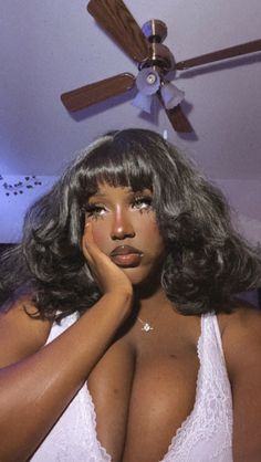 a woman with long hair wearing a bra and posing in front of a ceiling fan