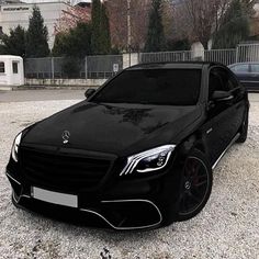 a black mercedes s - class parked in gravel