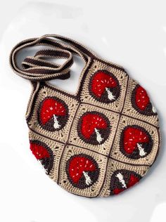 a crocheted purse with red and brown designs on it's front, sitting on a white surface