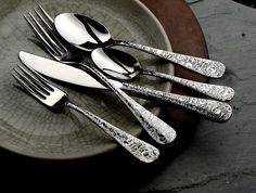 four forks and two spoons on a plate with silverware in the shape of flowers