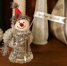 a snowman with a hat and tinsel on it's head sitting in a vase