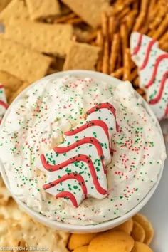 a white bowl filled with whipped cream surrounded by crackers and pretzel sticks