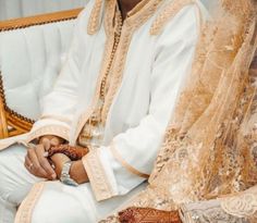 a man and woman sitting next to each other on a couch in wedding attire with veils over their heads