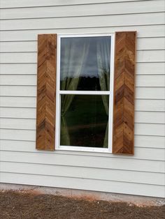 a white house with wood trim on the window and grass in front of it,