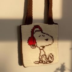 a crocheted bag hanging on a wall with a dog wearing a santa hat