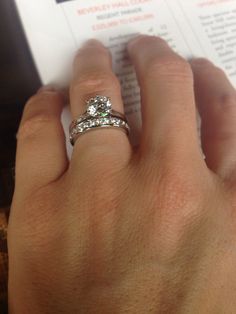 a close up of a person's hand with a ring on top of a book