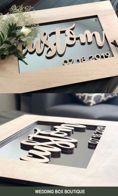 two wooden signs that are sitting on top of a table with flowers in the middle