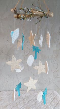 a wind chime hanging from a tree branch with sea shells and starfishs on it